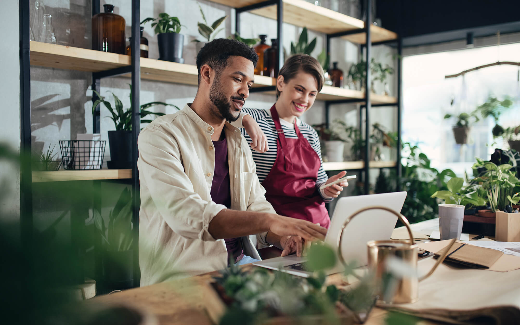 Shop owners with laptop working in potted plant store